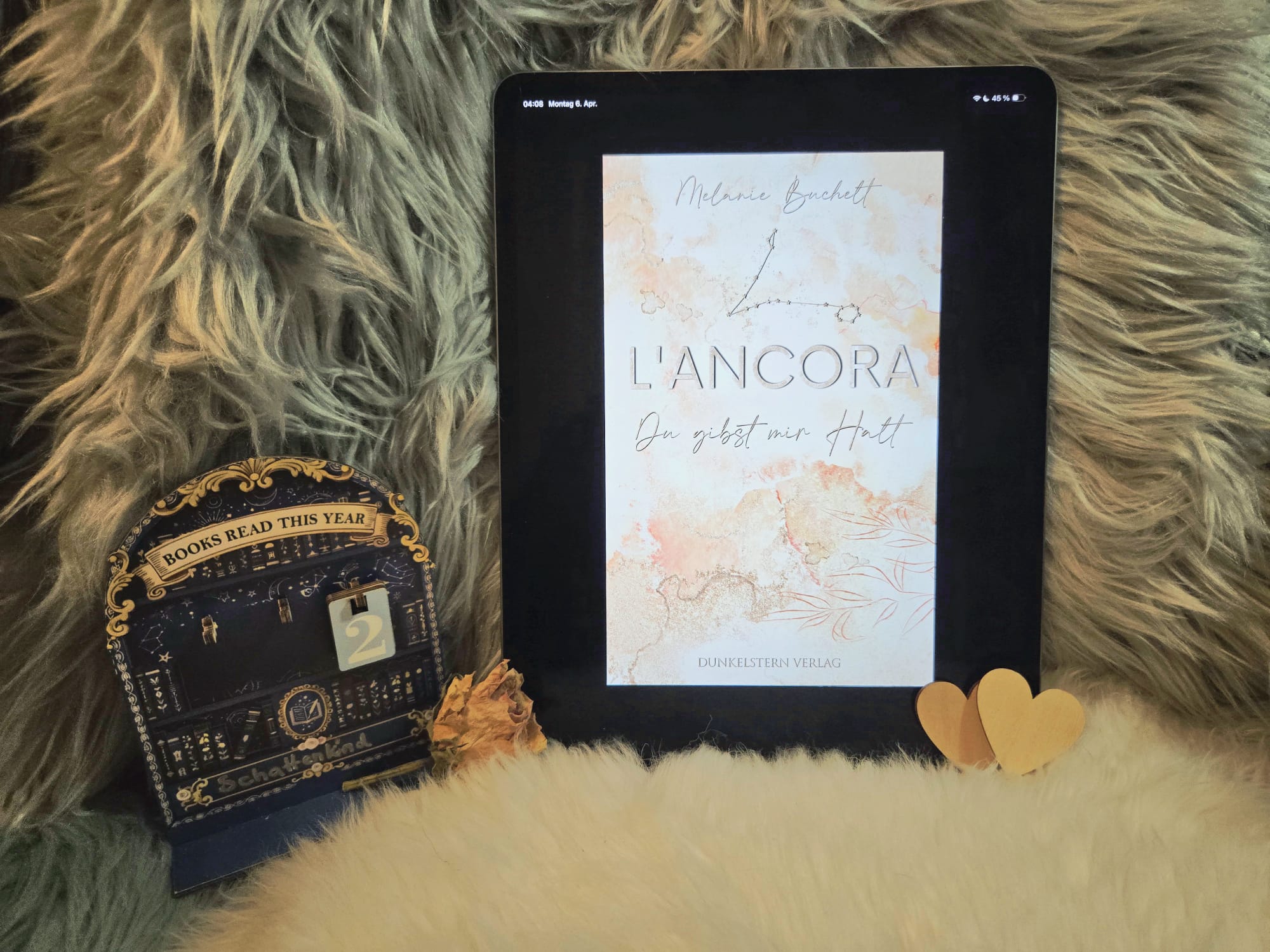 Lancora An iPad displaying the book cover 'L'ANCORA: Du gibst mir Halt' by Melanie Buchelt and a tracker showing 2 books read this year.